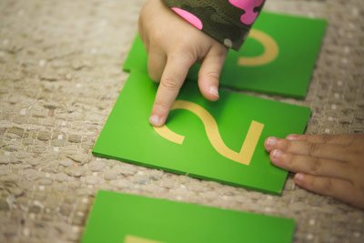 A picture of a young child tracing the number two with their index finger.